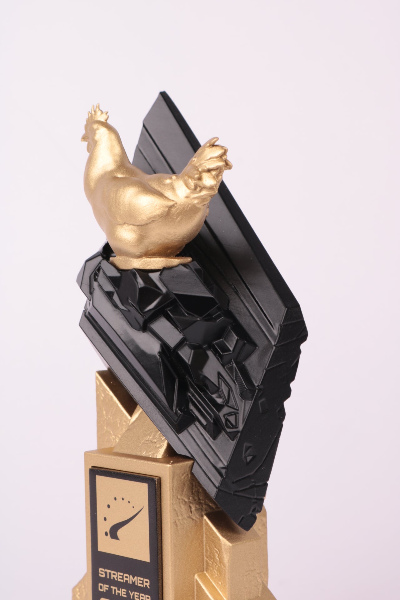 gold trophy with a 3d printed black trophy on top with a gold chicken